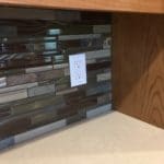backsplash of cabinet multi colored stacked tile, white electrical recepticle. wood cabinets