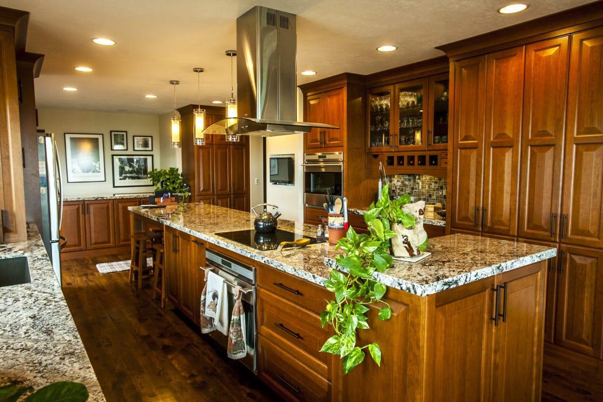 Kitchen with wood cabinets and granite counters. green plant on the counter.