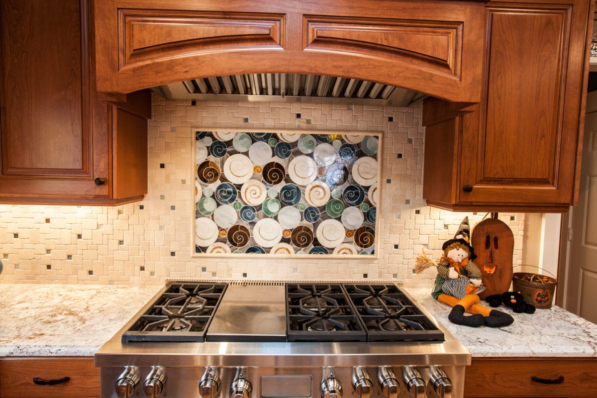 Large mosaic over a stove with cabinets over the stove