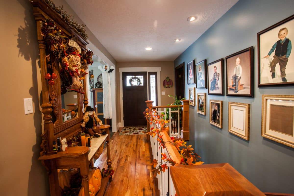 festive entryway with a large mirror on the left. large staircase on the right with photos along the wall