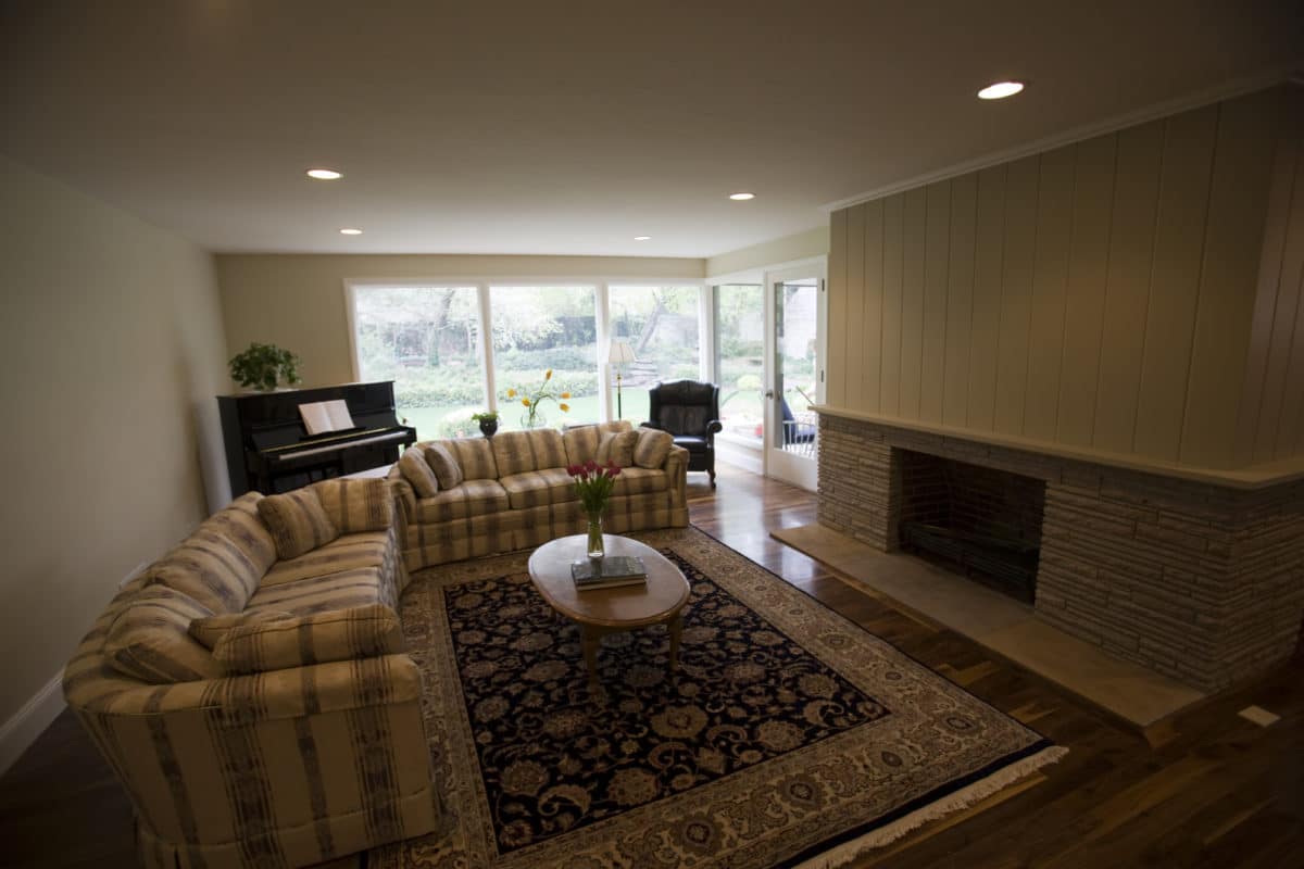 Large living room with striped couch on the left and fireplace on the right wall.
