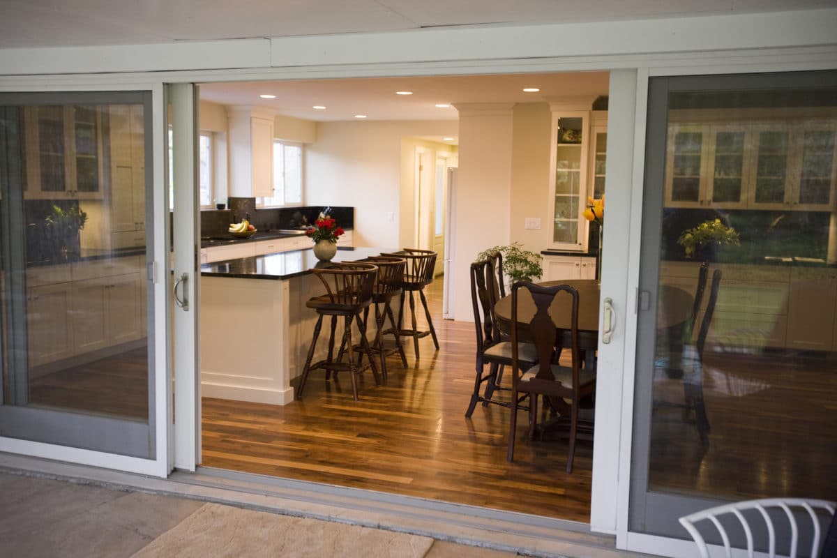 view of kitchen through the back patio doors. large kitchen island on the right and kitchen table on the left