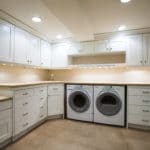 classic white cabinets in laundry room uppercabinets and front loading washer and dryer wood floor