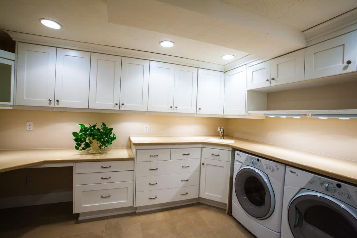 bright laundry room with white cabinets and the washer and dryer on the right.