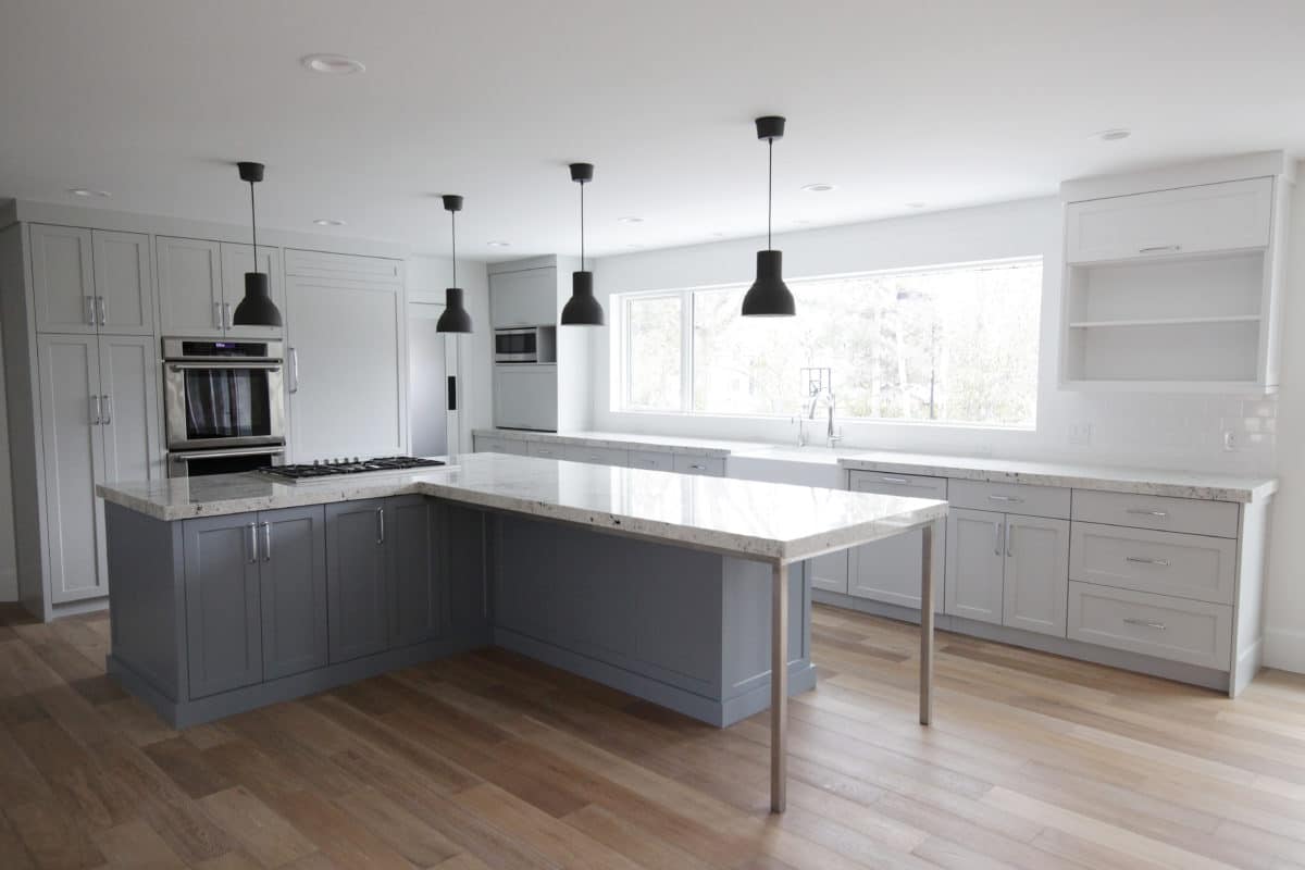 White kitchen with large island on the left and hanging pendants