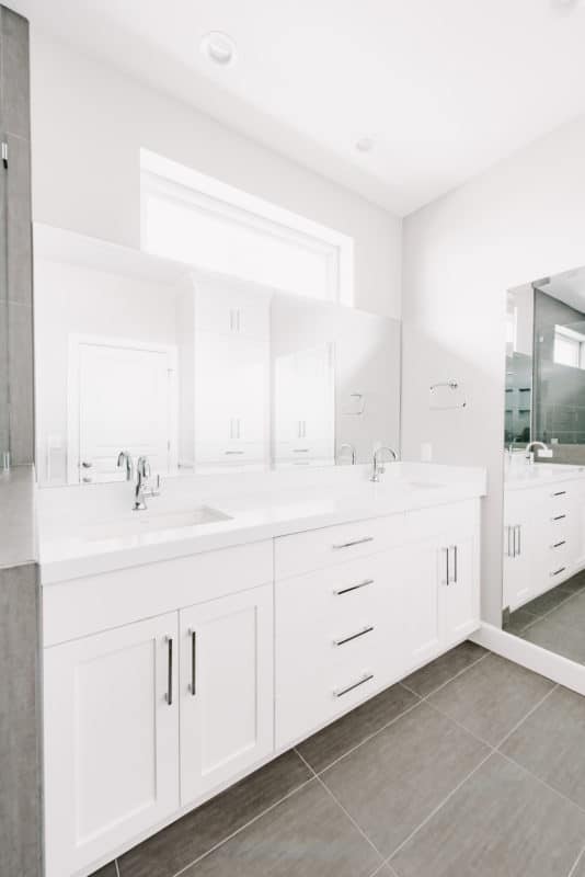 White vanity in newly remodeled bathroom large mirror