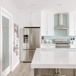 stainless steel appliances in a newly remodeled kitchen. white cabinets dark island and white countertops