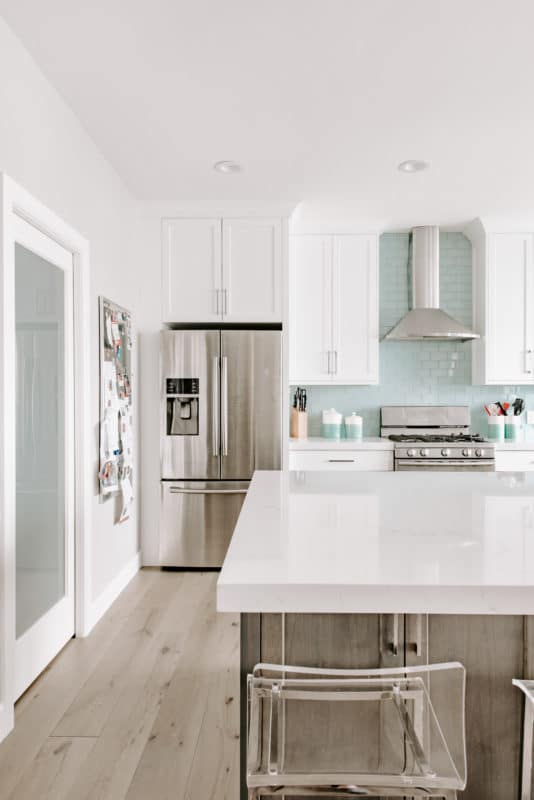 stainless steel appliances in a newly remodeled kitchen. white cabinets dark island and white countertops