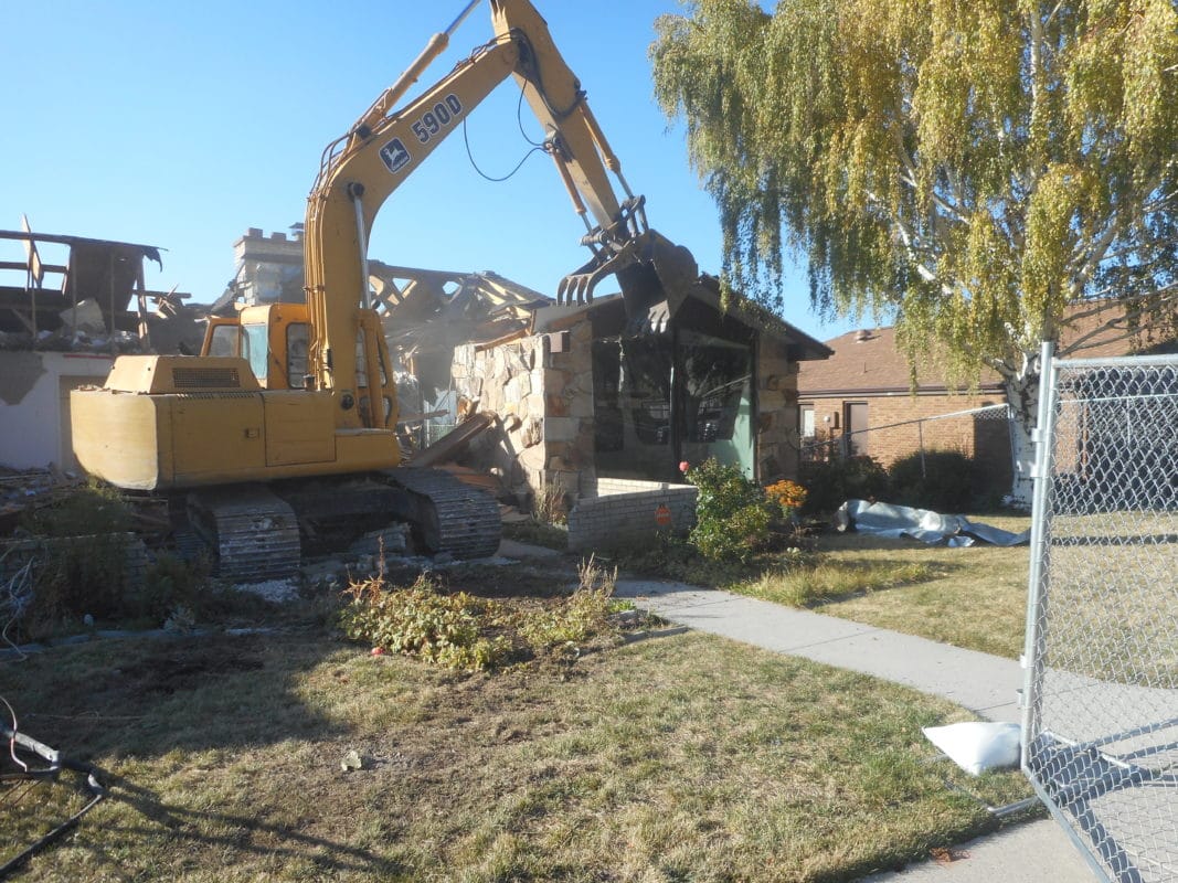 home being torn down by an excavator for a new home build