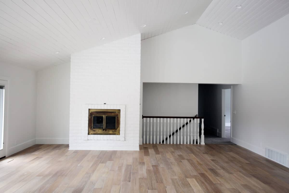 White fireplace wall with wood stair case.