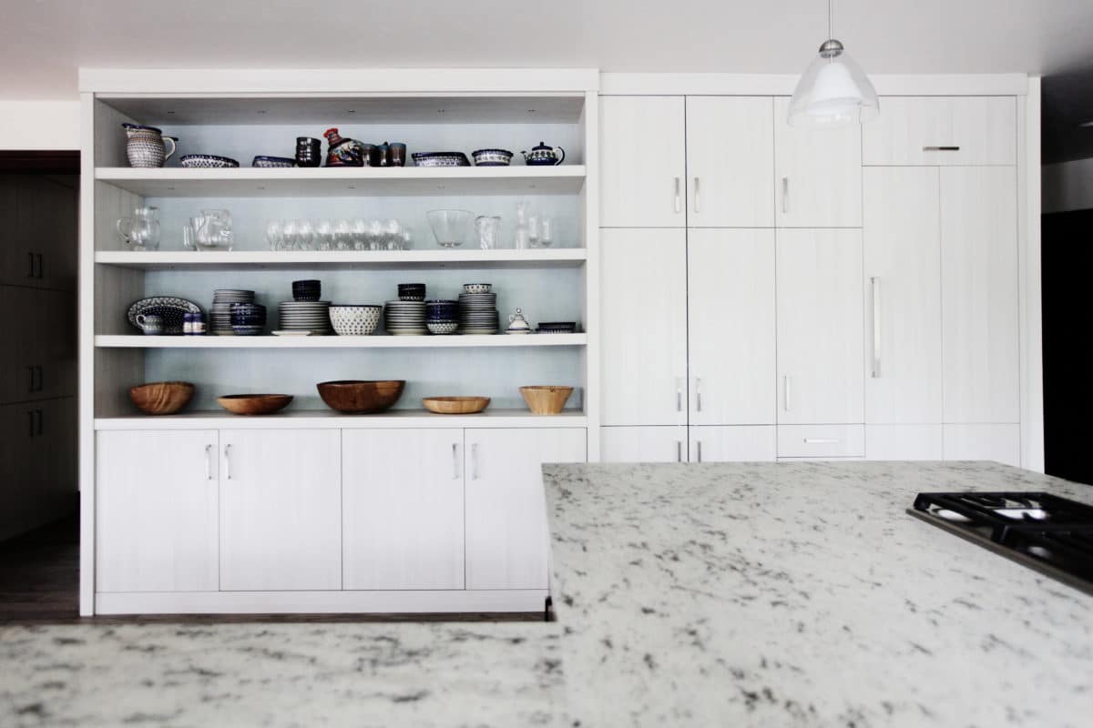 white wall of cabinetry, white shelving unit. granite countertop.