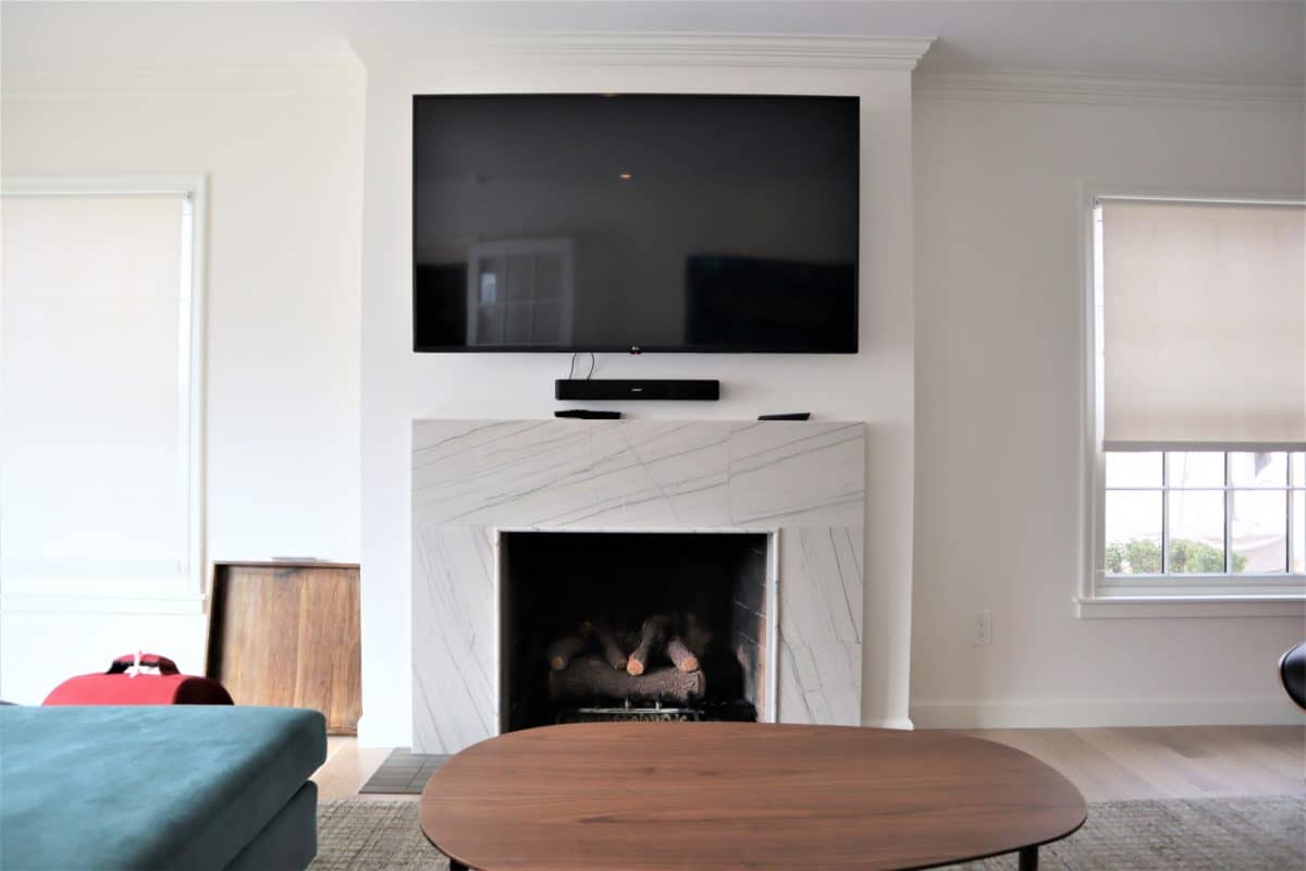white marble fireplace surround with tv over the mantel top in remodeled family room
