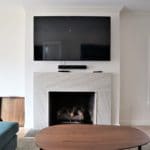 white marble fireplace surround with tv over the mantel top in remodeled family room