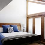 Master bedroom with frosted glass doors on the right and a large bed in the middle