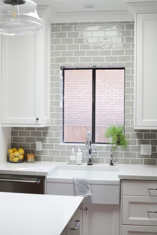 farmhouse sink and white cabinets, gray tile around window