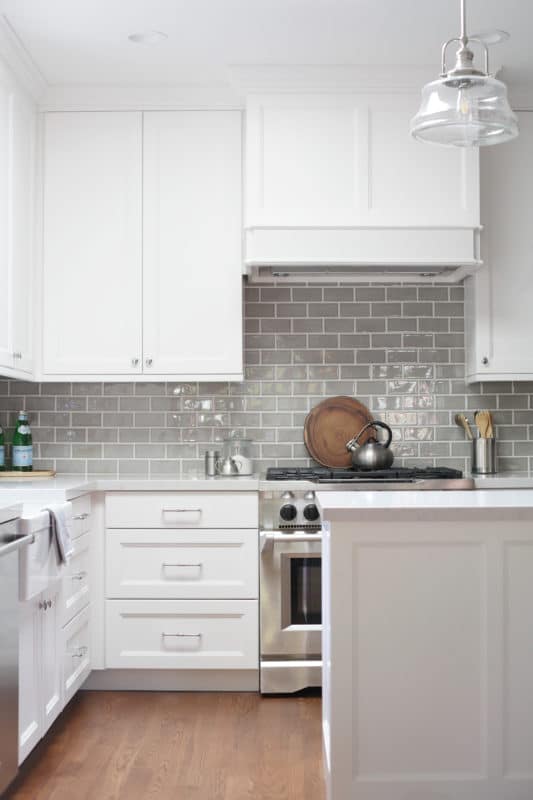 white kitchen with gray backsplash. silver stove and island