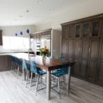 Blue chairs and blue pendants in this dark wood kitchen with integrated table and island