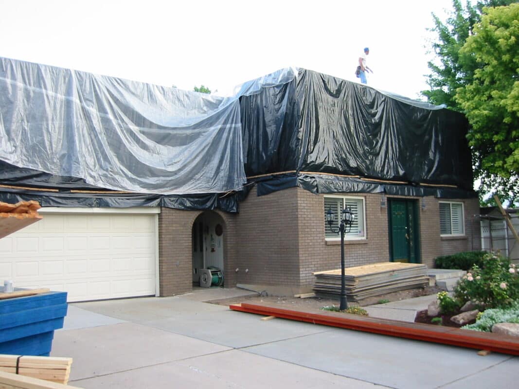 Brick home covered in Black tarp and clear tarp during framing