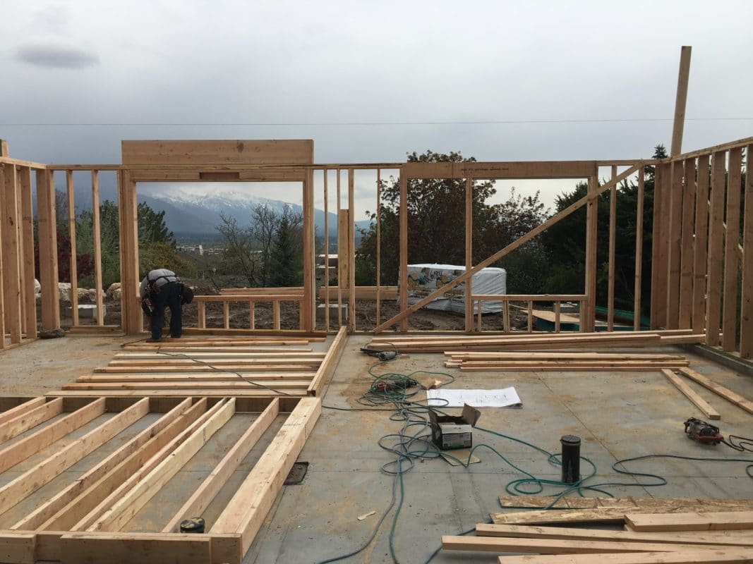 beginning of framing for new home build. one wall starting to go up other 2x4s being staged on the ground