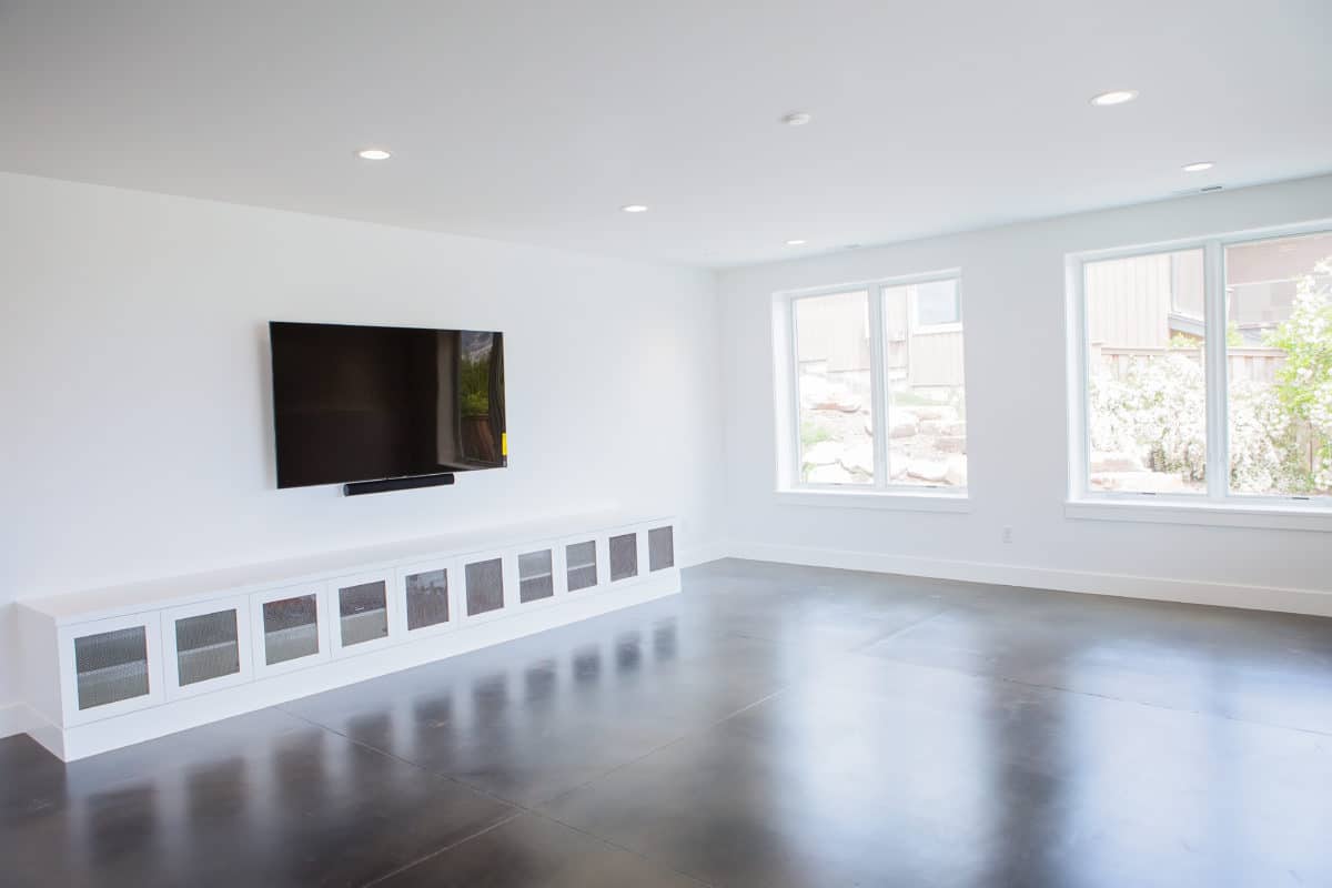 daylight basement with polished concrete floors and white paint on walls. mounted tv and built in storage along the floor