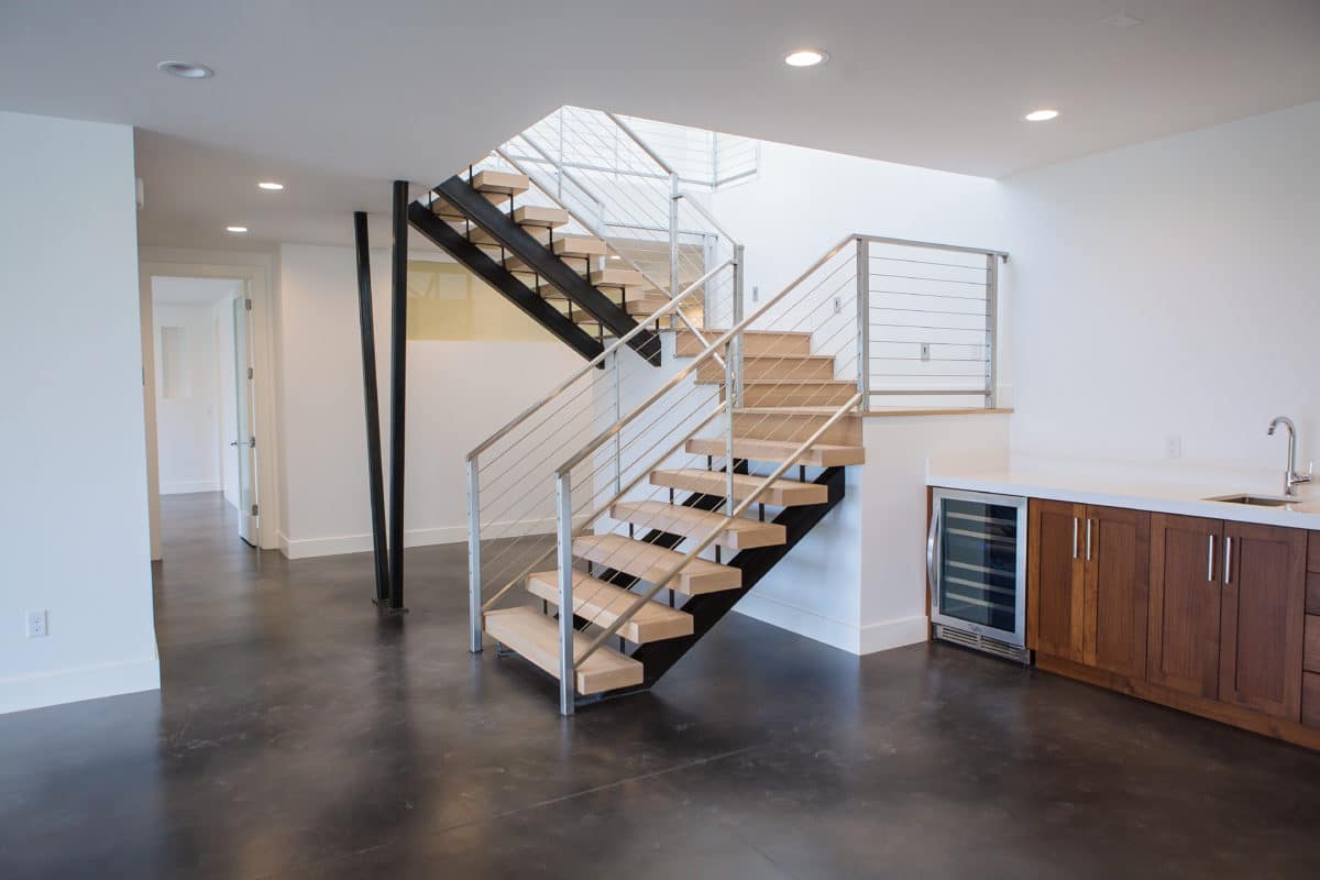 stairs with wood treads in basement with polished cement floors and white walls