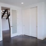 bedroom in basement of a new home build. polished cement floors white walls double frosted glass doors