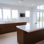 kitchen in premier new home build light wood floors darker cabinets and white countertops