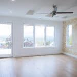 large great room in new custom home build. metal ceiling fan white walls and multiple windows door