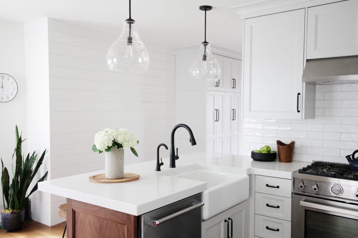 kitchen remodel with clear glass pendant lights black faucet, white cabinets and stainless steel dishwasher