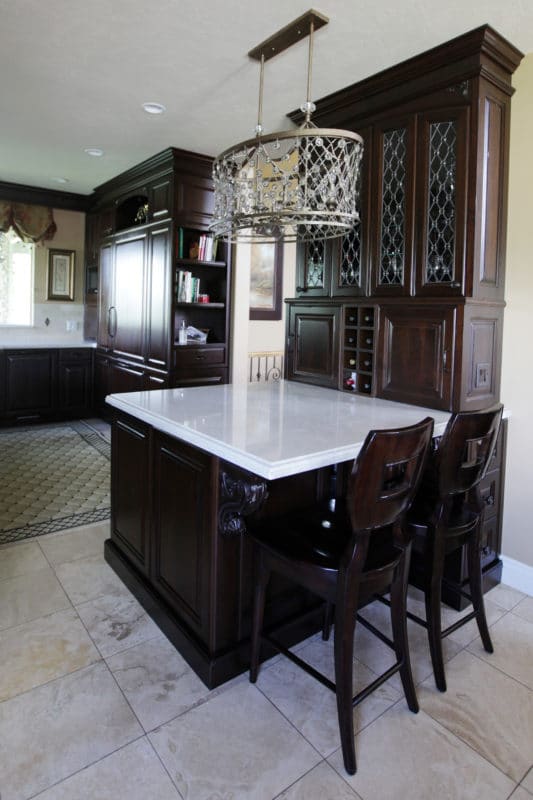 dark wood cabinets with white countertop and crystal chandelier