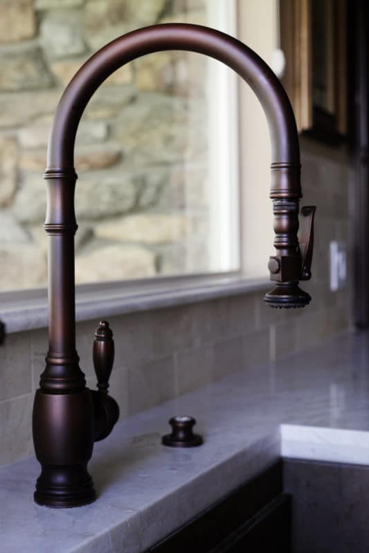 dark copper kitchen faucet with white countertop around sink