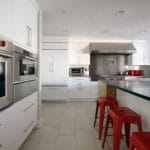 white gloss cabinets, red stools stainless steel appliances