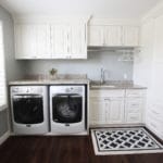 Laundry room Washer and Dryer with white cabinets and a sink