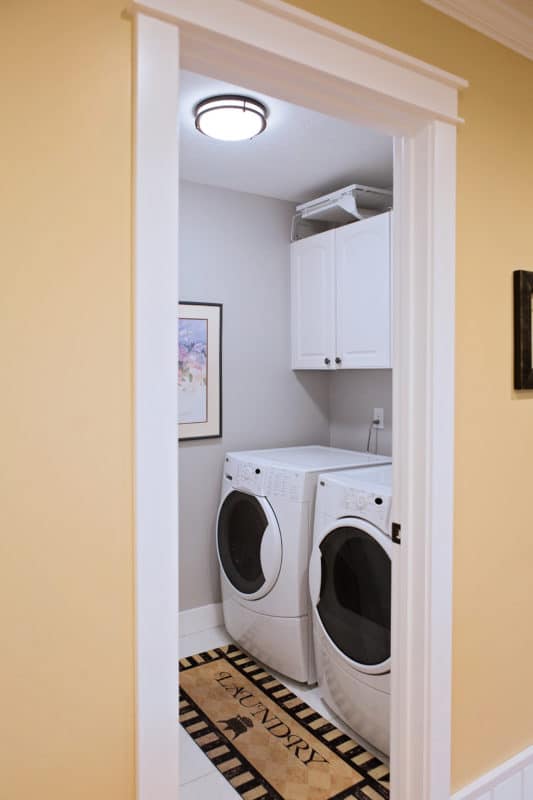 laundry room looking in through doorway, washer and dryer side by side with cabinets above