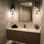 Half bath remodel in Utah with lighted floating vanity, marble counter top, and black modern bathroom light fixtures by Fine Remodel