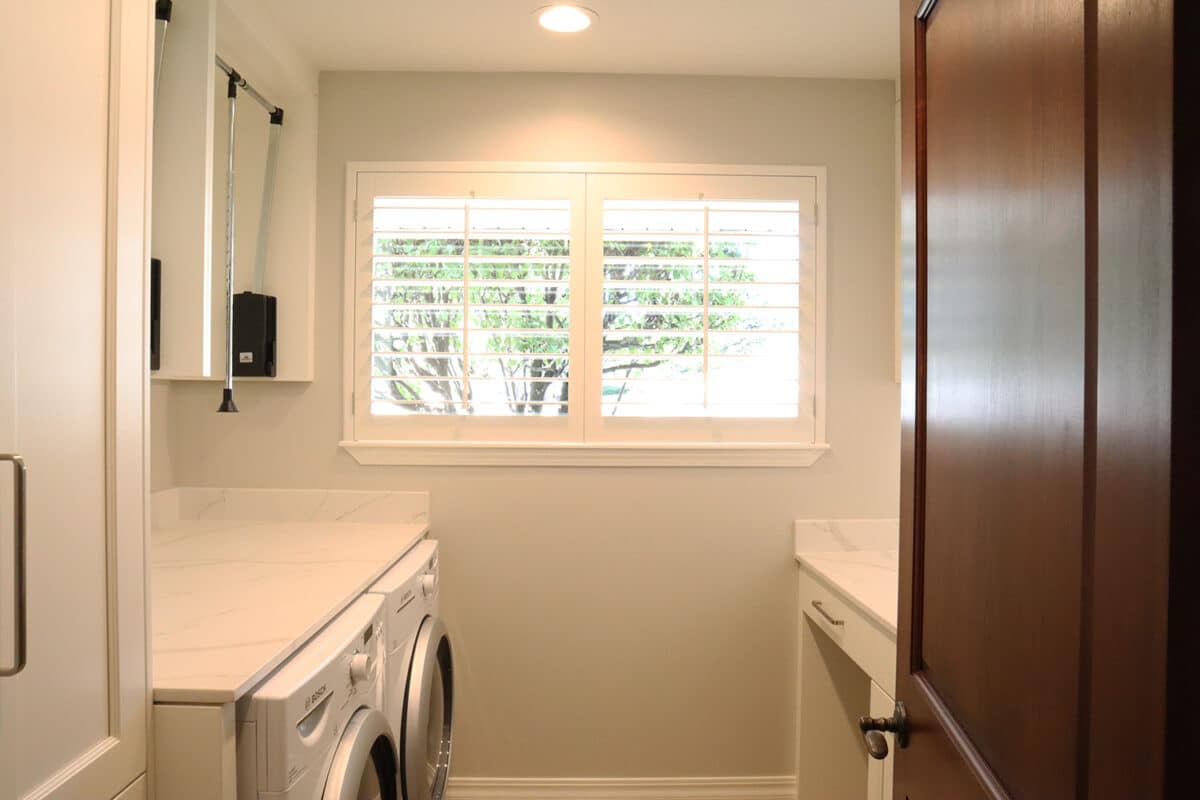 Newly remodeled contemporary laundry room with marble waterfall countertops for laundry room machines by Fine Remodel