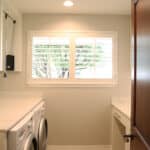 Newly remodeled contemporary laundry room with marble waterfall countertops for laundry room machines by Fine Remodel