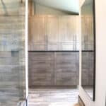 Hall view of laundry room from bathroom. This space showcases natural wood floors with matching floor to ceiling cabinetry and laundry room island