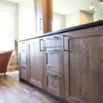 Luxurious custom wood cabinets in bathroom with matching wood flooring and copper claw-foot bathtub